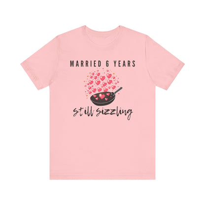 Pink anniversary t-shirt with the text Married 6 Years Still Sizzling around a cartoon frying pan and hearts