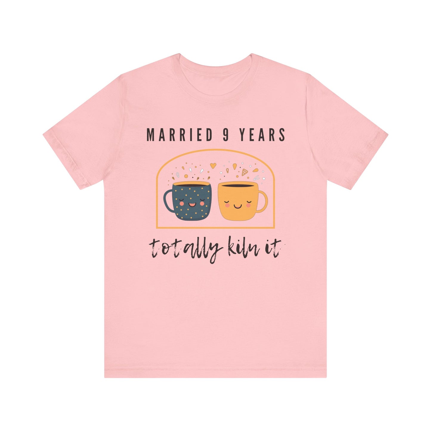 Pink anniversary t-shirt with the text Married 9 Years Totally Kiln It around two cartoon cups in a pottery kiln